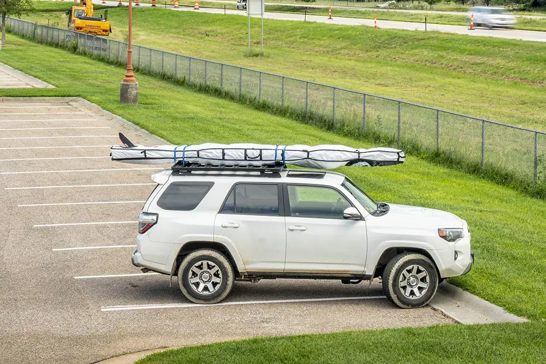 Witte auto met een board in een beschermhoes op dakdragers